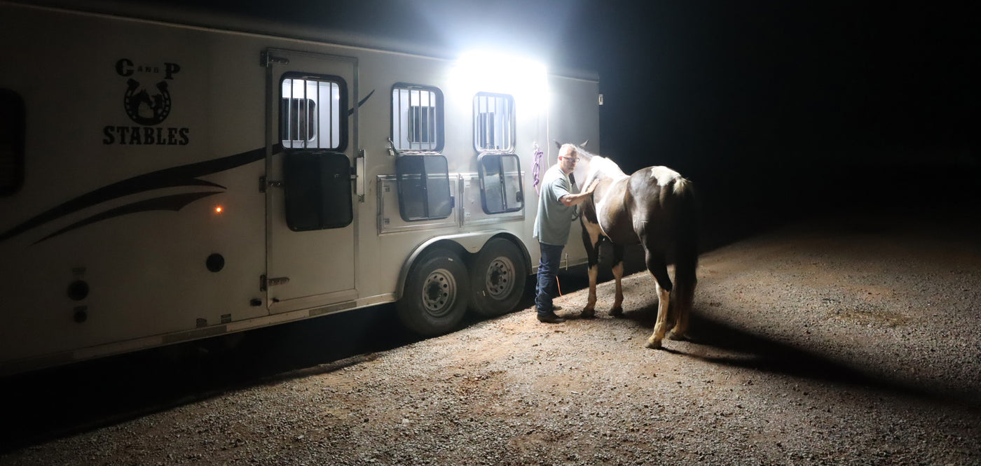 Horse trailer with LED lighting. Pit Viper side mount horse trailer light with a horse and cowboy beside the trailer at night.